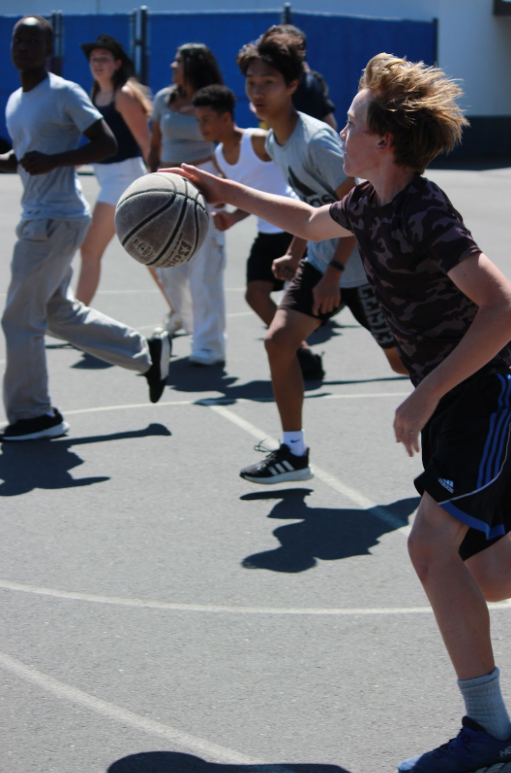 A basketball player rushes down the court while his teammates and opponents follow along (Photo By: Linbert Ngnitang).
